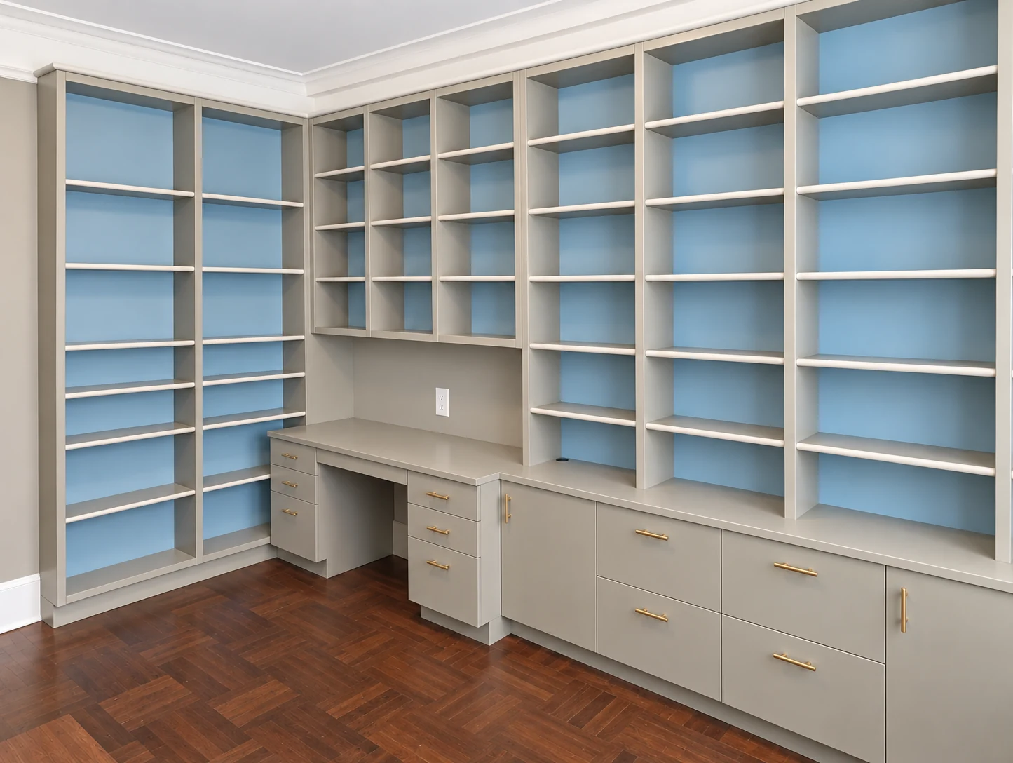 Painted bookcases with blue backs, lower cabinets and an integrated work surface wrapping a New York library