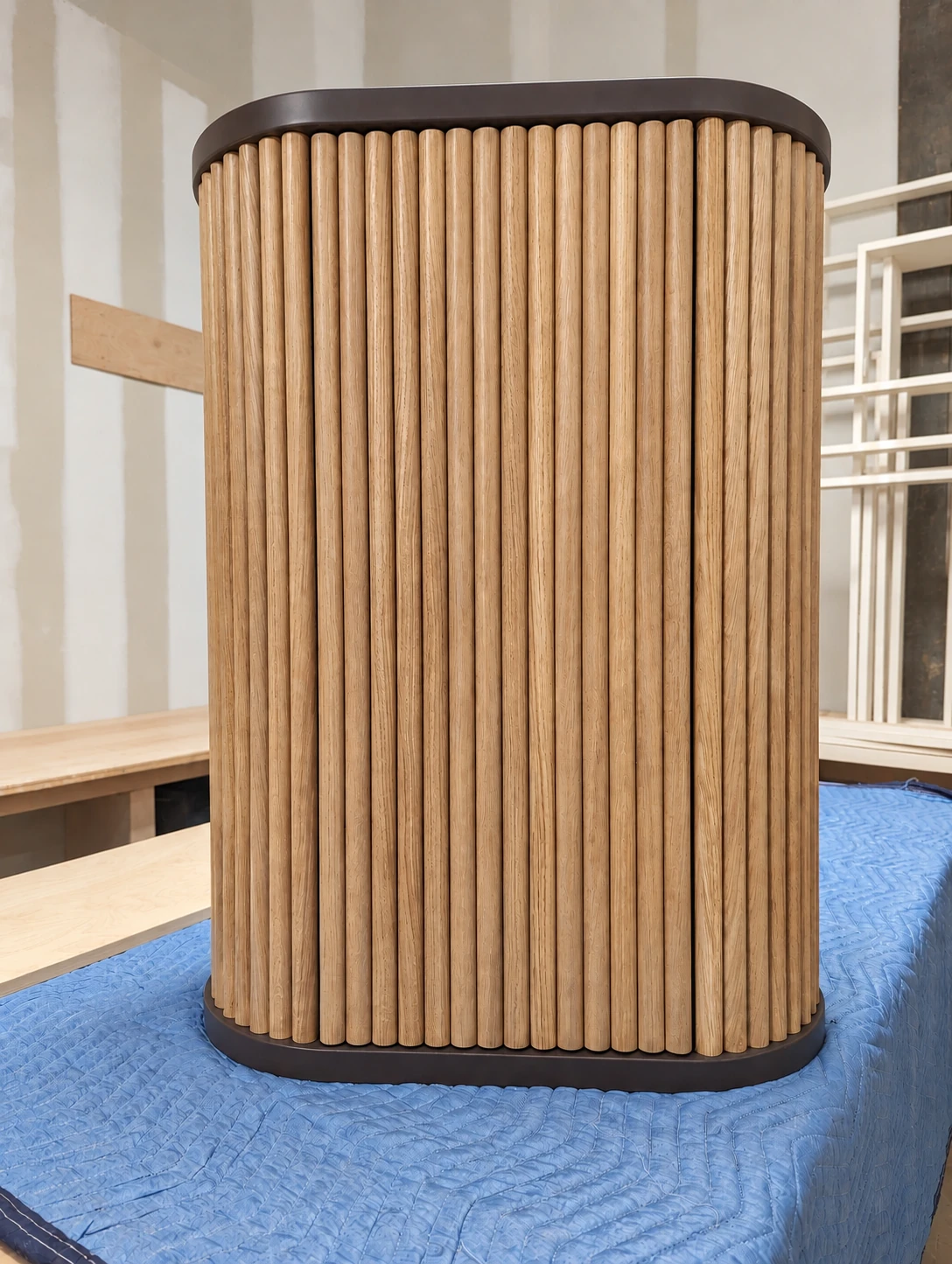Complete curved wood cabinet with vertical oak fluting and dark upper and lower rims on a protected JQ workshop table