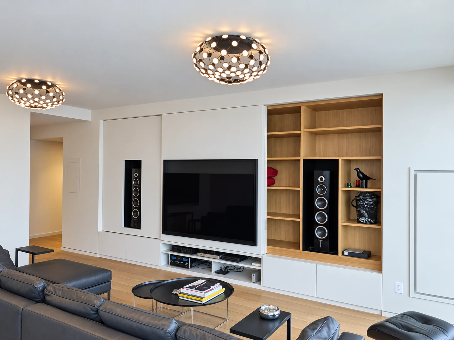 Painted sliding media wall in the Flatiron District with a television, two recessed speakers, open wood display shelves and lower audio equipment storage