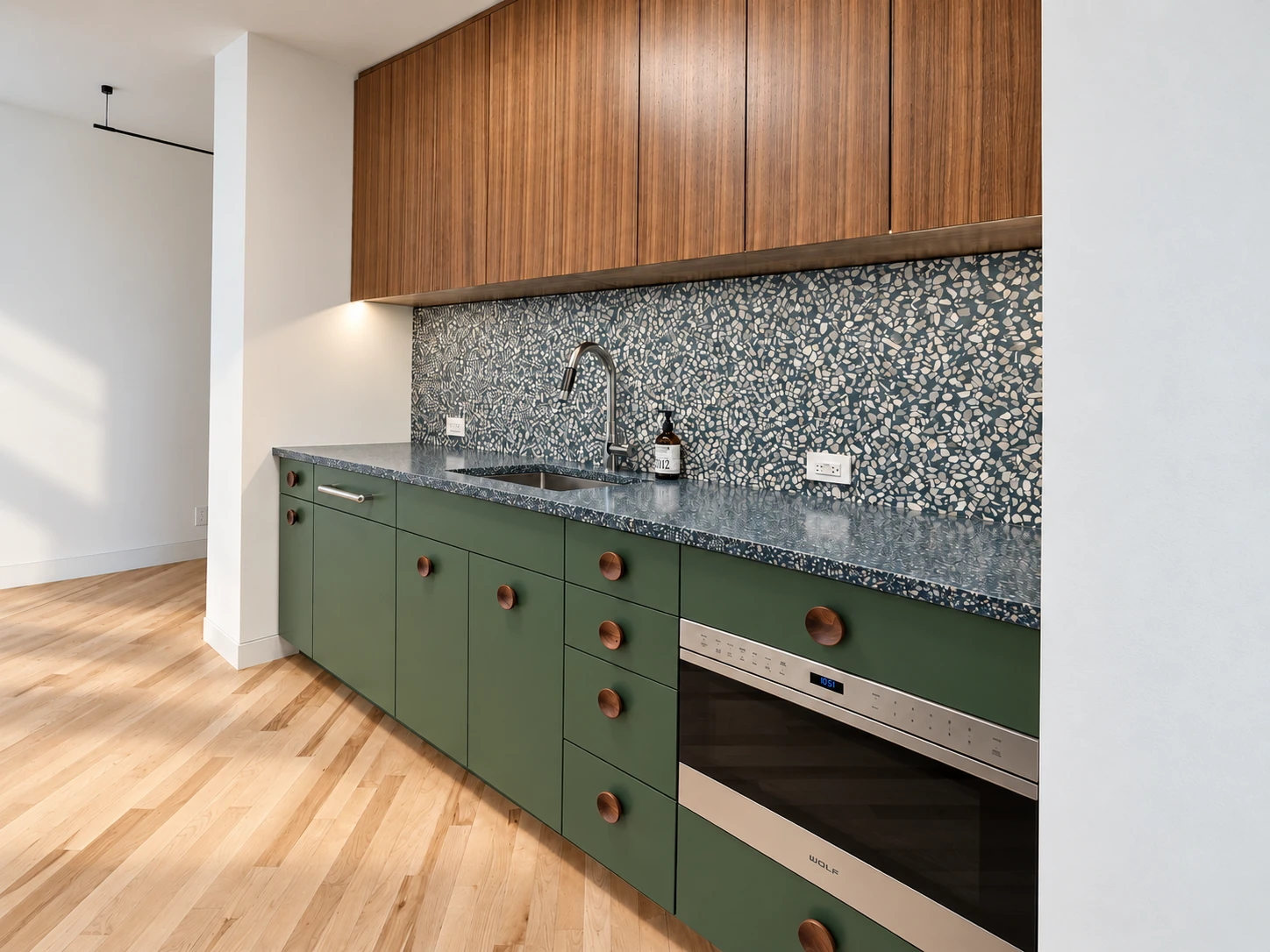 Lower Manhattan kitchen with rift-cut walnut veneer upper cabinets, custom-painted green base cabinets and a speckled backsplash