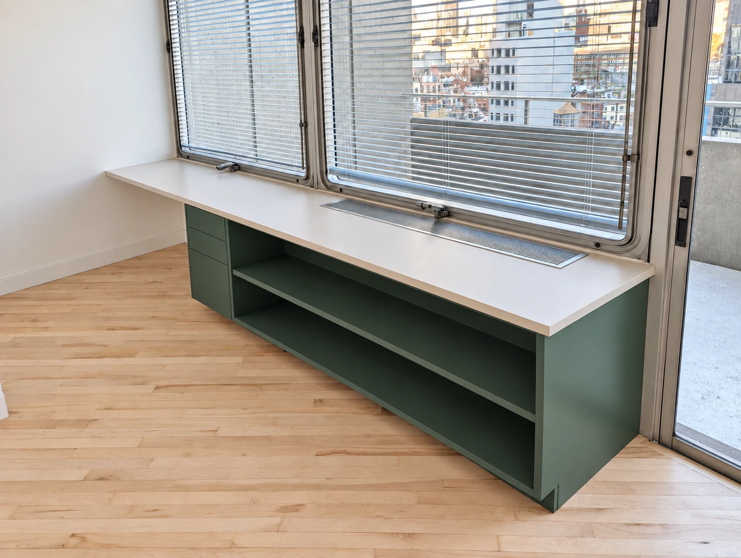 Green open shelving and fitted storage below the windows in Lower Manhattan