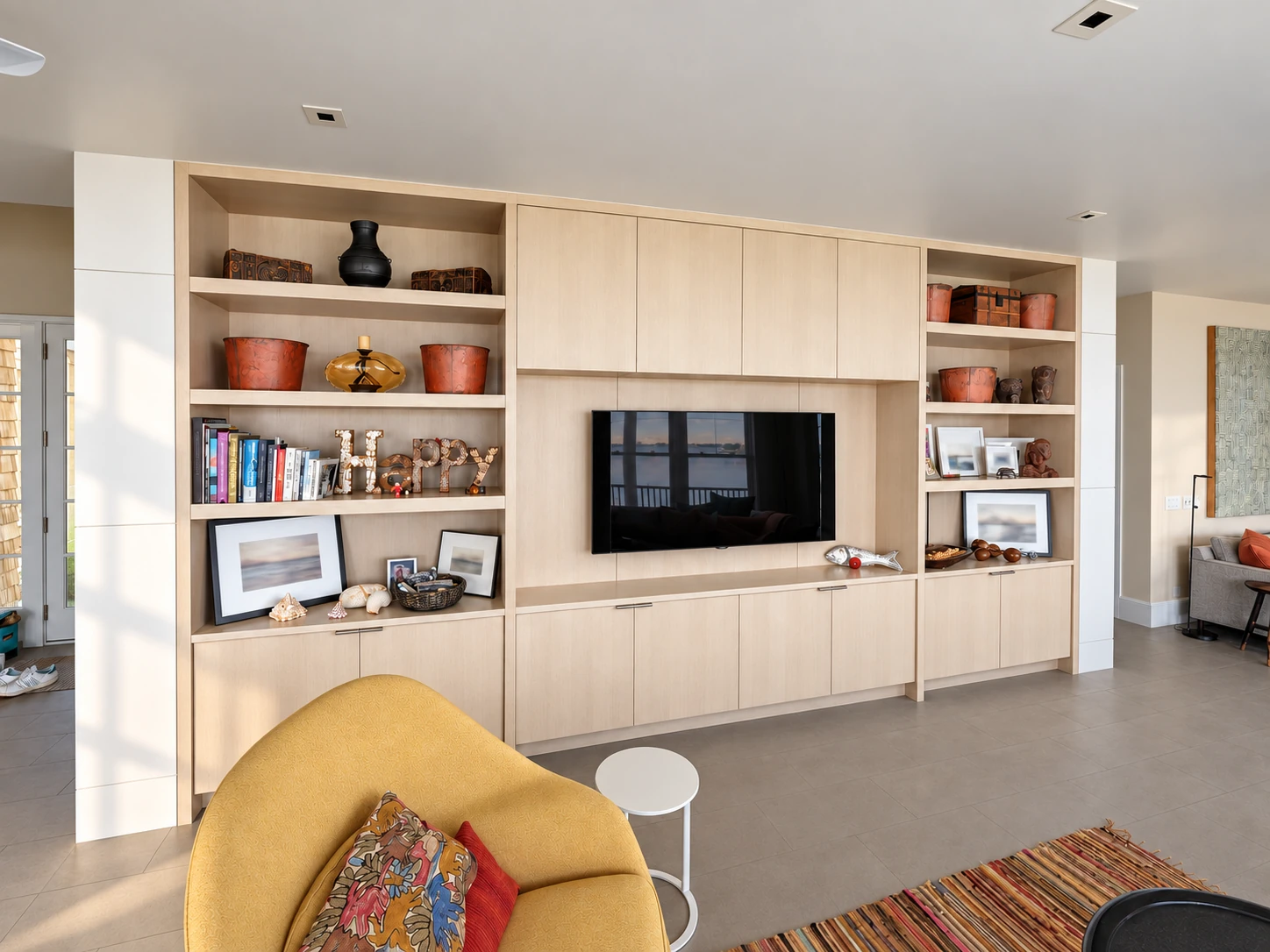 Light wood media cabinetry with open display shelves in a Westhampton Beach living room