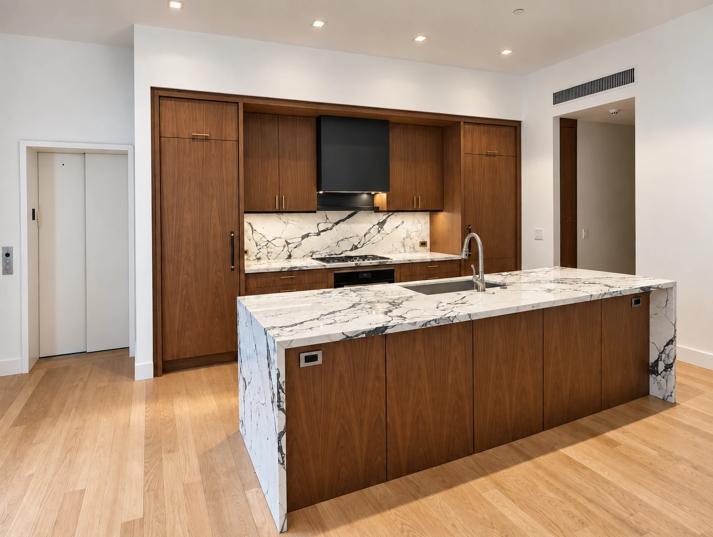 JQ kitchen in SoHo with wood cabinetry, a stone waterfall island and brass-tone fixtures